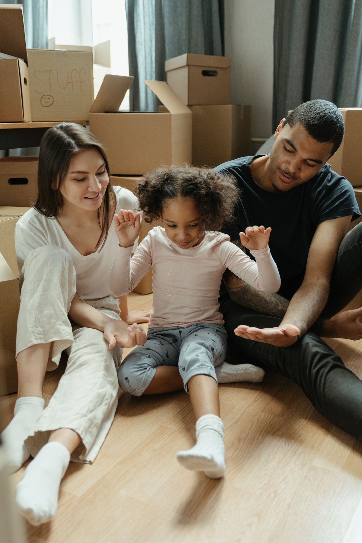 Parents and their young daughter unpacking together on the floor of their new home